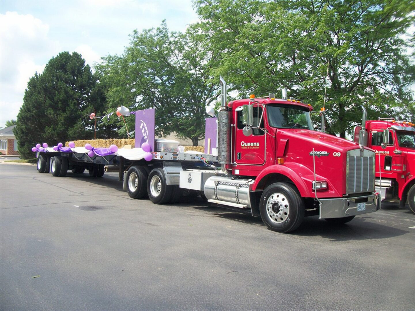 Red semi truck with purple balloon-decorated flatbed