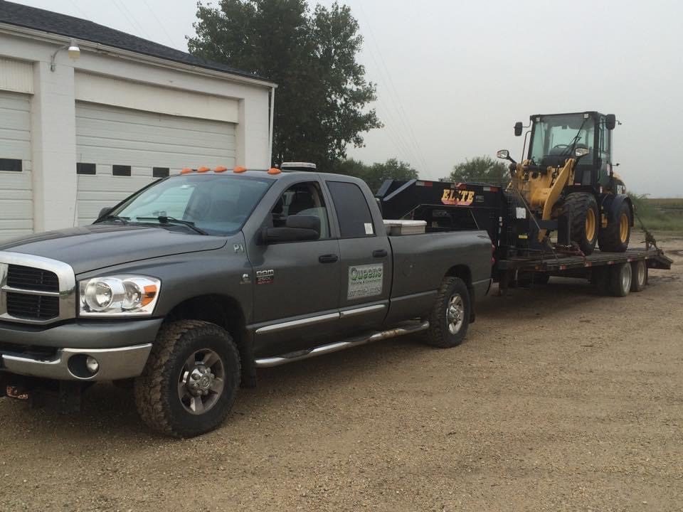 Pickup truck towing backhoe on flatbed trailer