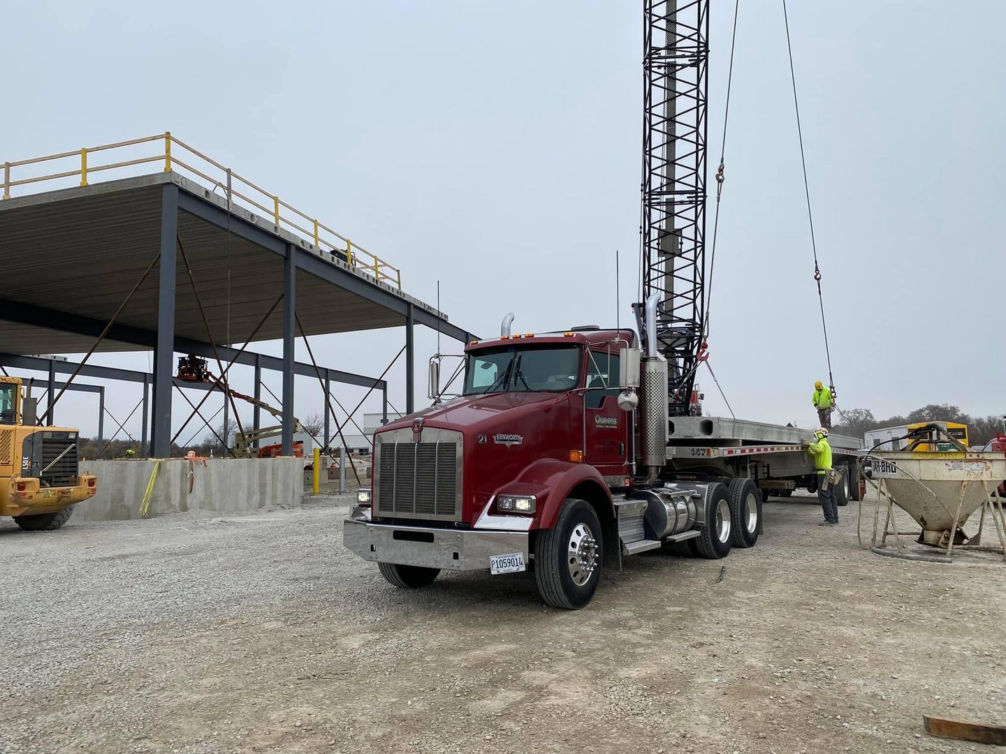 Red flatbed truck and crane at construction site