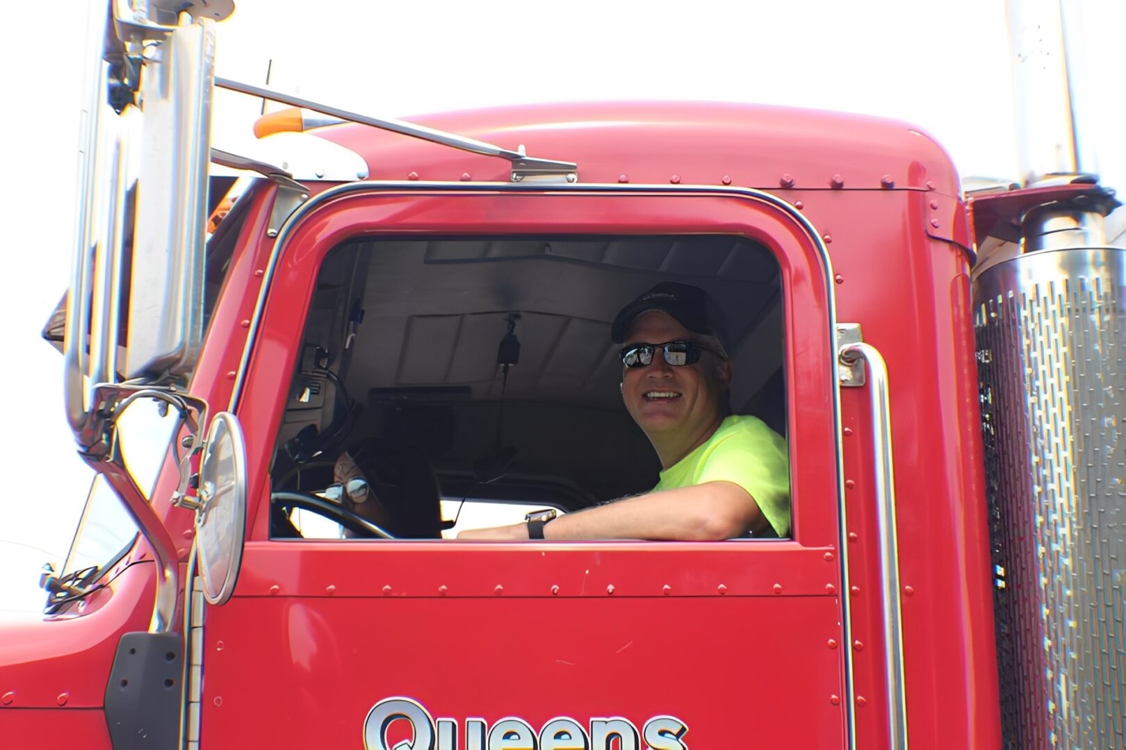 Driver in neon shirt inside red truck.