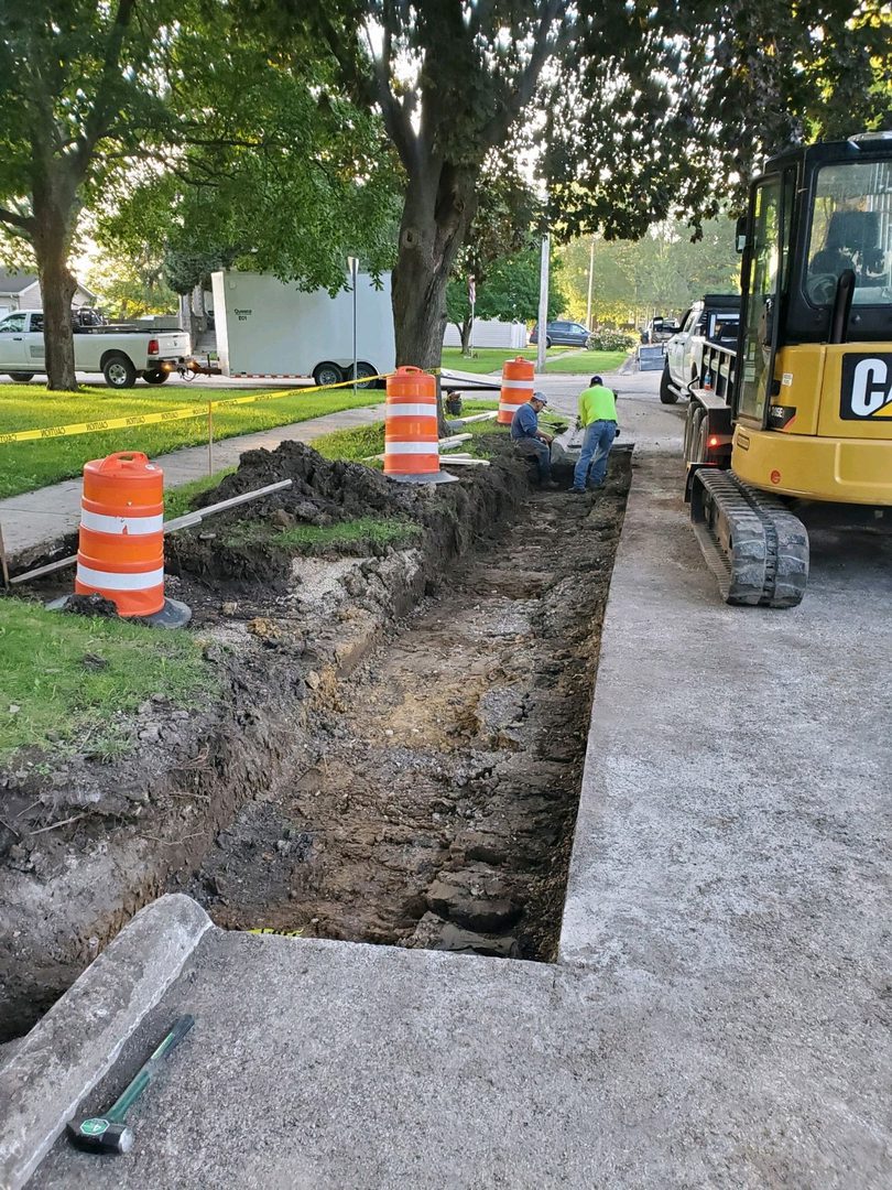 Construction workers digging trench by sidewalk