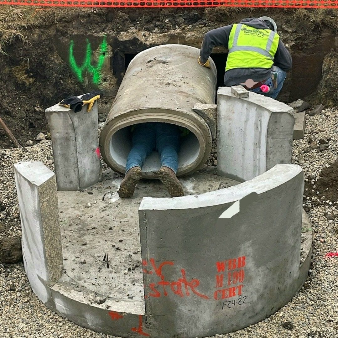 Construction worker entering concrete pipe
