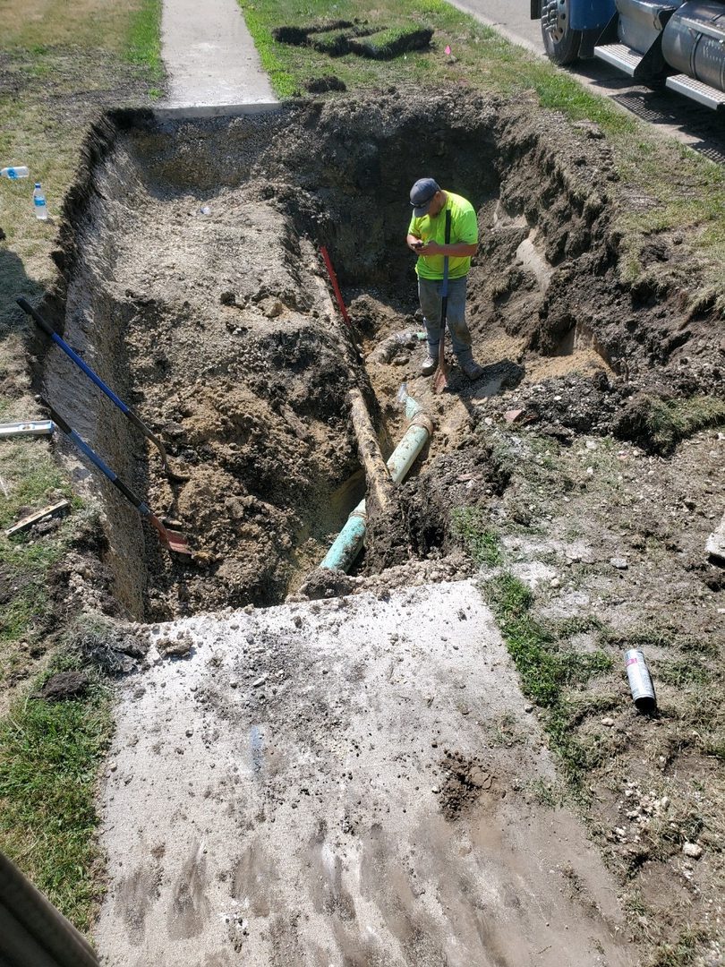 Construction worker inspecting large pipe trench