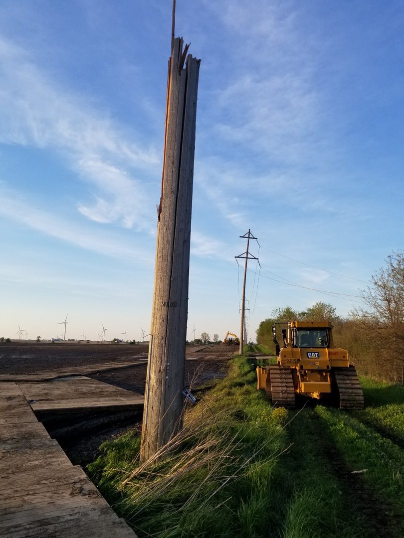 Utility pole snapped with machinery nearby