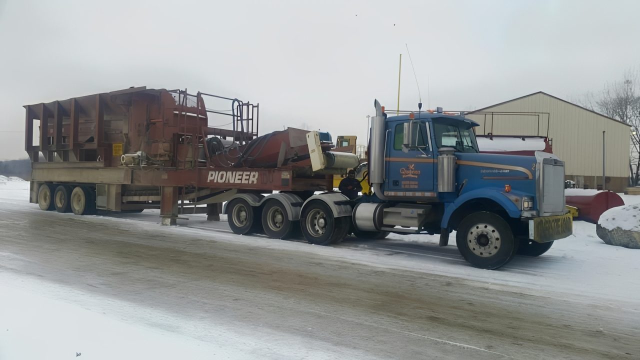 Blue truck hauling large industrial equipment