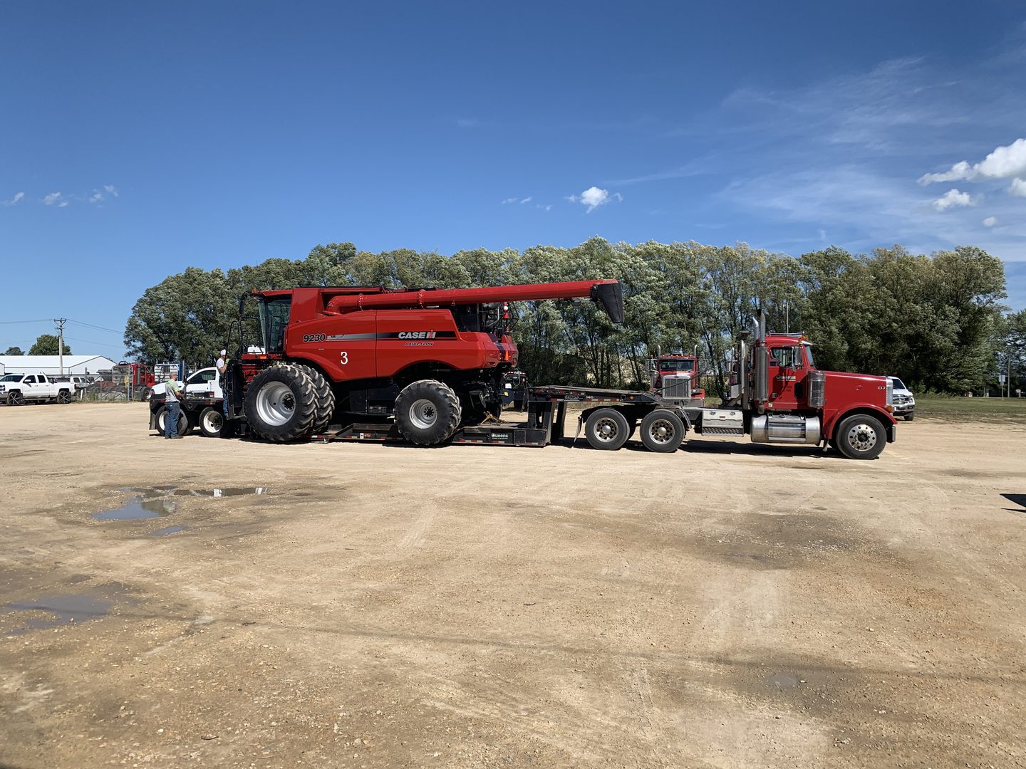 Red combine harvester loaded on flatbed trailer