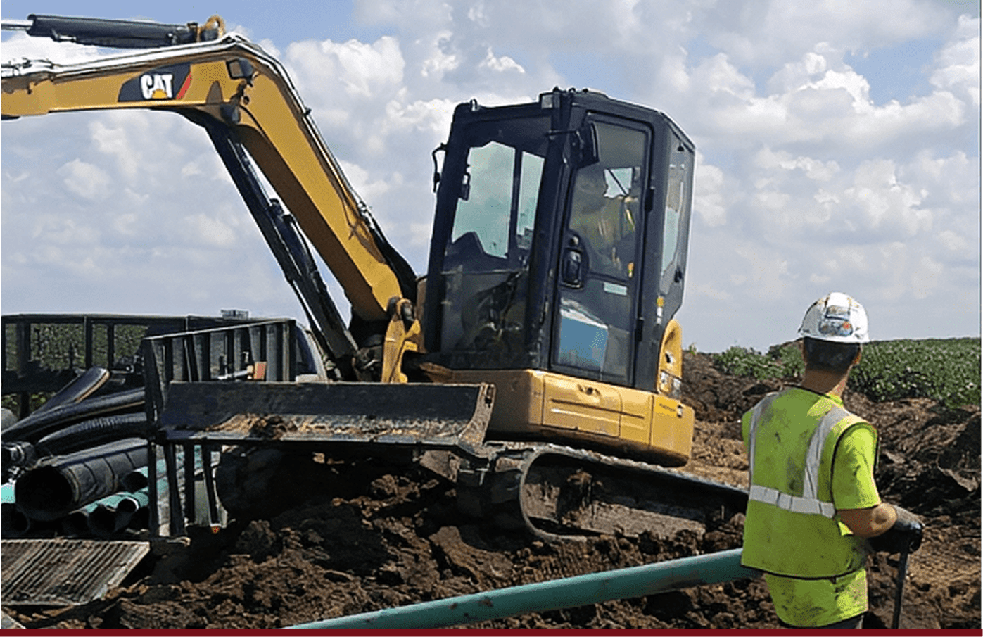 Yellow excavator and worker near green pipes