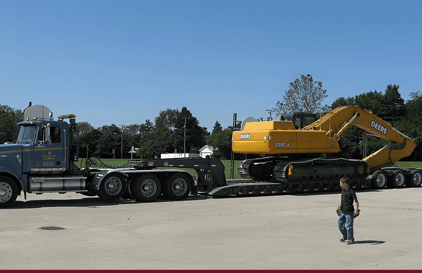 Yellow Deere excavator on lowboy trailer