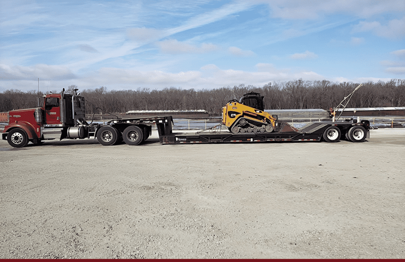 Red truck hauling yellow compact track loader